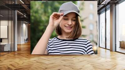 Portrait of smiling woman in baseball cap outdoors Wall mural