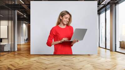 Portrait of young woman with modern laptop on light grey background Wall mural