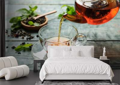 pouring black tea into glass cup on wooden table Wall mural