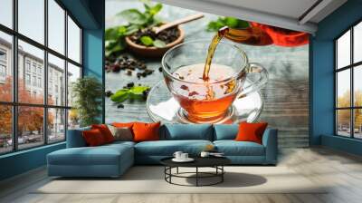 Pouring black tea into glass cup on wooden table Wall mural