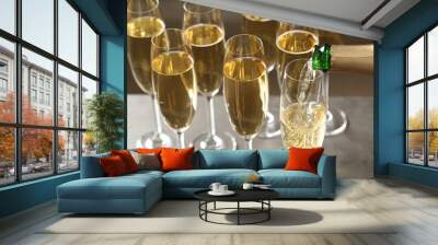 Pouring champagne into glasses on table, closeup view Wall mural