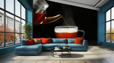 Pouring delicious hot tea into glass cup on table against dark background Wall mural