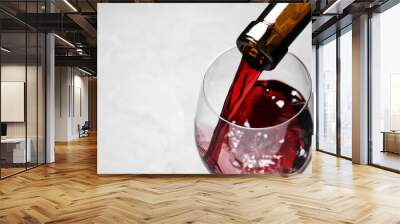 Pouring red wine from bottle into glass on light background, closeup. Space for text Wall mural