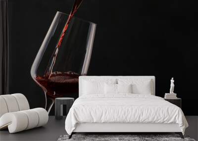 Pouring red wine into glass on dark background. Space for text Wall mural