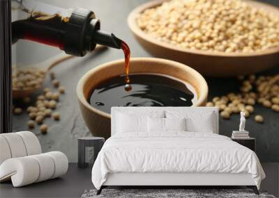 Pouring tasty soy sauce from bottle into bowl on black table, closeup Wall mural