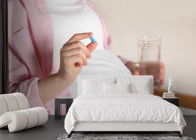 Pregnant woman taking pill in armchair, closeup. Space for text Wall mural