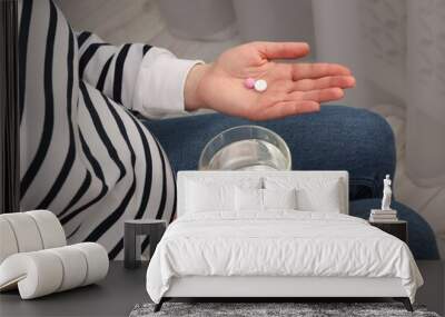 Pregnant woman with glass of water and pill at home, closeup Wall mural