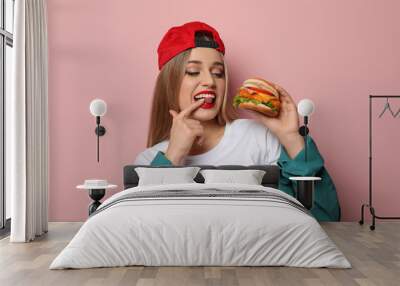 Pretty woman with tasty burger on color background Wall mural