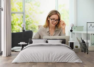 Pretty young woman working with laptop in office Wall mural