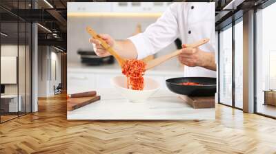 Professional chef putting delicious spaghetti into bowl at marble table in kitchen, closeup Wall mural