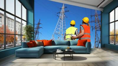 Professional electricians in uniforms near high voltage towers Wall mural