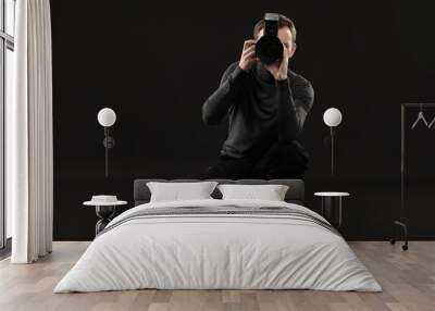 Professional photographer taking picture on black background Wall mural