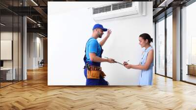 Professional technician speaking with woman about air conditioner indoors Wall mural