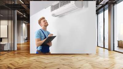 Professional technician with clipboard near modern air conditioner indoors Wall mural