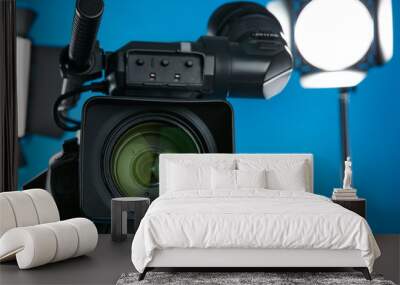 Professional video camera and lighting equipment on blue background, closeup Wall mural