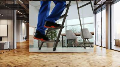 Professional worker climbing up ladder in room, closeup. Space for text Wall mural