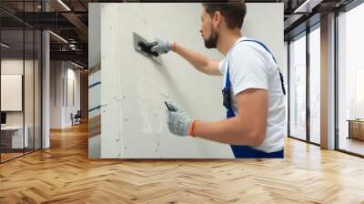 Professional worker plastering wall with putty knives indoors Wall mural