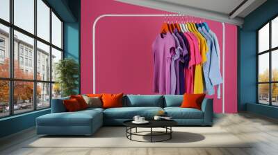 Rack with stylish children clothes on pink background Wall mural