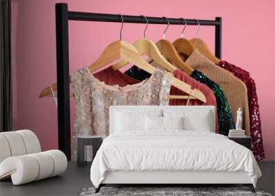 Rack with stylish women's clothes on wooden hangers against pink background Wall mural