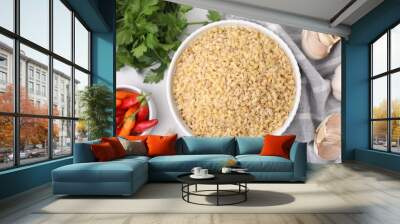 Raw bulgur in bowl and spices on table, flat lay Wall mural