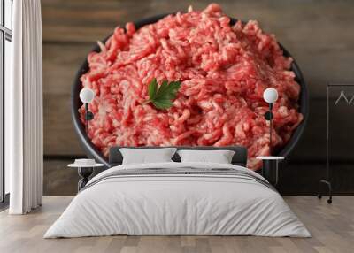 Raw ground meat and parsley in bowl on wooden table, closeup Wall mural