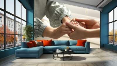 Religious women holding hands and praying together near window indoors, closeup Wall mural