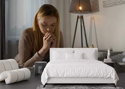 Religious young woman praying over Bible in bedroom Wall mural