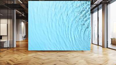 Rippled surface of clear water on light blue background, top view Wall mural