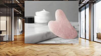 Rose quartz gua sha tool and jar of cream on white marble table, closeup Wall mural