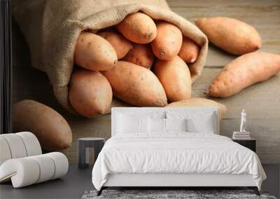 Sack with fresh raw sweet potatoes on wooden table, closeup Wall mural