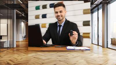 Salesman with car key at desk in office Wall mural