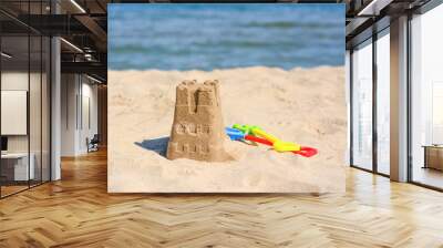 Sand castle and child plastic toys on beach near sea Wall mural