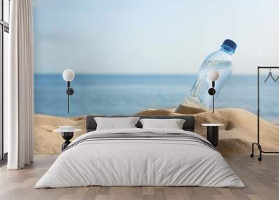 Sandy beach with bottle of refreshing drink on hot summer day, space for text Wall mural