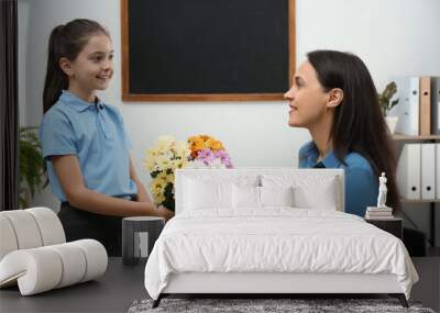 Schoolgirl congratulating her pedagogue with bouquet in classroom. Teacher's day Wall mural