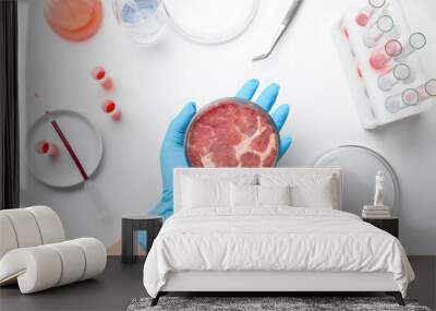 Scientist holding Petri dish with cultured meat above white lab table, top view Wall mural