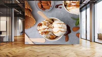 Scoops of ice cream with caramel sauce and nuts on light grey table, flat lay Wall mural