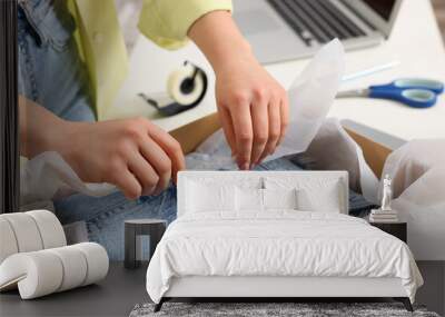 Seller packing jeans into cardboard box at workplace, closeup Wall mural