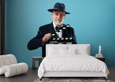 Senior actor with clapperboard on light blue background. Film industry Wall mural