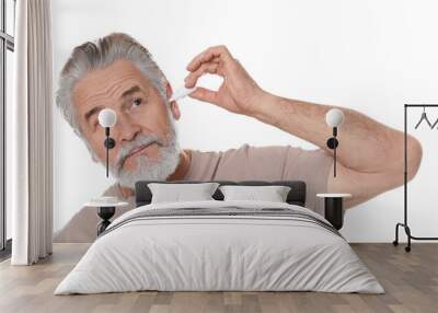 Senior man using ear drops on white background Wall mural