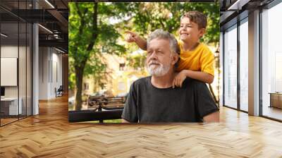 Senior man with his little grandson resting together in park Wall mural