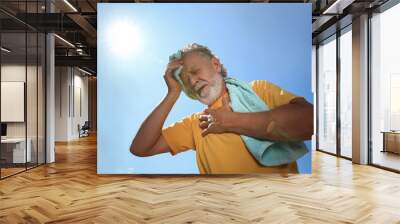 Senior man with towel suffering from heat stroke outdoors, low angle view Wall mural