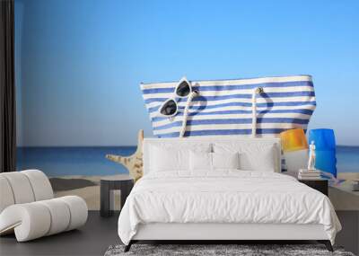 Set with stylish beach accessories on sand near sea Wall mural