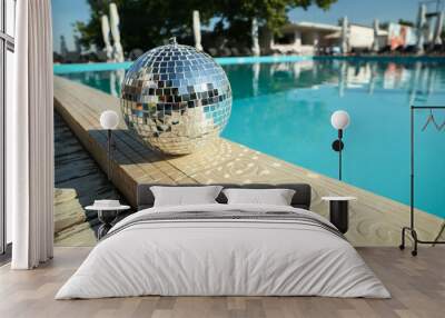 Shiny disco ball on edge of swimming pool. Party decor Wall mural