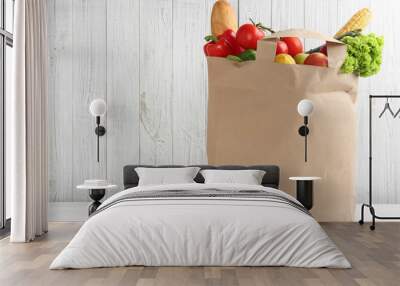 Shopping paper bag with different groceries on table against white wooden background. Space for text Wall mural