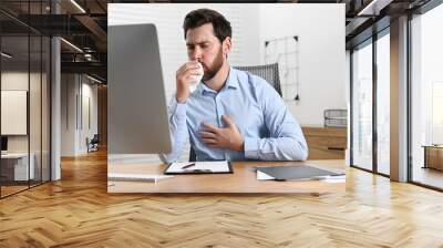 Sick man with tissue coughing at workplace in office Wall mural