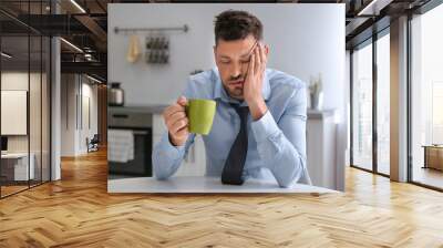 Sleepy man with cup of drink at home in morning Wall mural