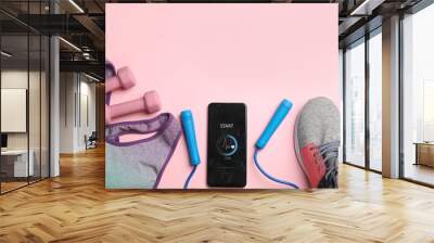 Smartphone with heart rate monitor app and fitness accessories on pink background, flat lay Wall mural