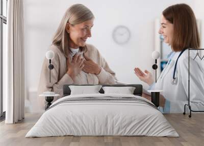 Smiling healthcare worker with tablet consulting senior patient in hospital Wall mural