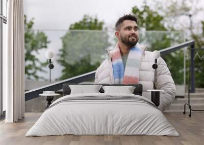 Smiling man in warm scarf outdoors, low angle view. Space for text Wall mural