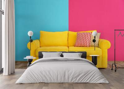 Sofa with different pillows near color wall in room Wall mural